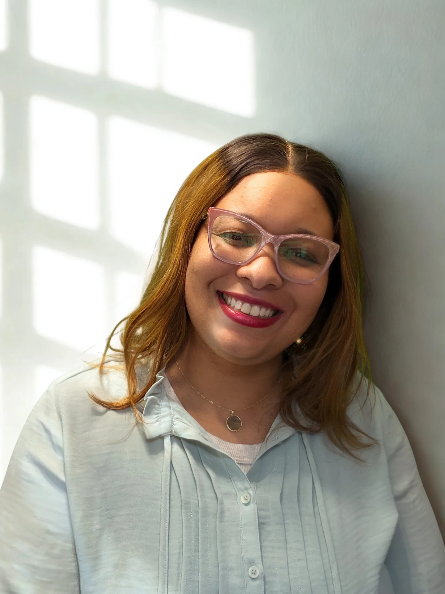Jackie Bommuluri smiling in front of a sunlit wall